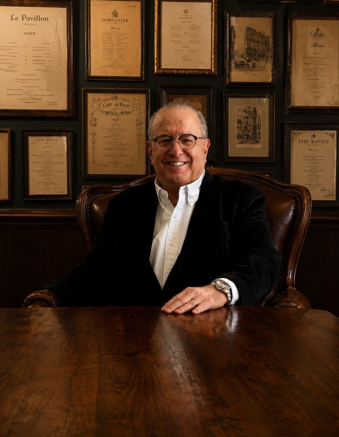 Theodore “Ted” Barber seated before a wall of framed vintage menus from the collection